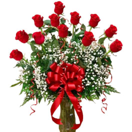 Bouquet of red roses with baby's breath in a glass vase and red ribbon