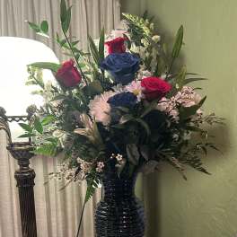 Mixed bouquet of roses and daisies in a dark vase