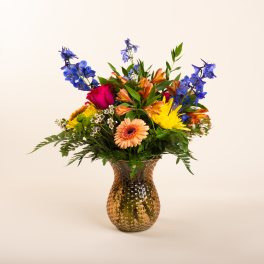 Mixed bouquet of colorful flowers in a hammered glass vase