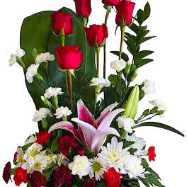 Tall floral arrangement with red roses, pink lilies, and white daisies in a black container