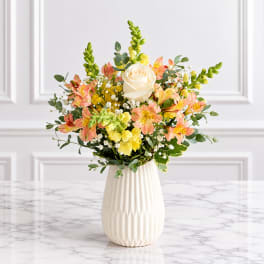 Bouquet of peach and yellow flowers in a white vase