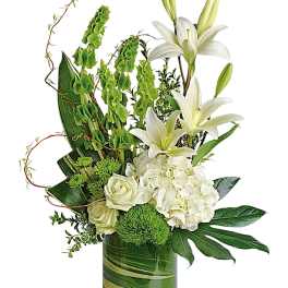 White lilies and roses in a green glass vase with green accents