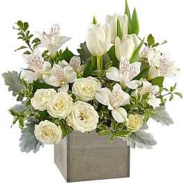 White tulips and roses in a square wooden vase with green foliage