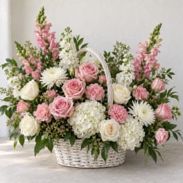 Basket arrangement of pink and white roses, carnations, and white blooms