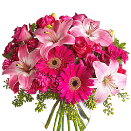 Pink lilies, roses, and gerbera daisies in a clear glass vase