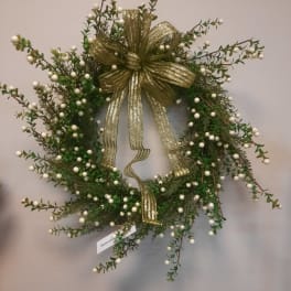 Green holiday wreath with white berries and a gold ribbon bow