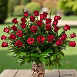 Red roses arranged in a patterned vase with rose petals on a wooden table