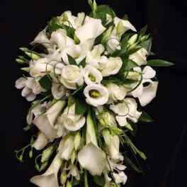 Cascading bouquet of white calla lilies, roses, and lisianthus against a black background