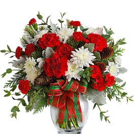Red carnations and white chrysanthemums in a glass vase with a plaid ribbon