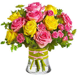 Pink and yellow roses in a clear glass vase with ribbon