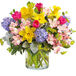 Mixed bouquet of yellow daffodils, pink tulips, and lavender flowers in a glass vase