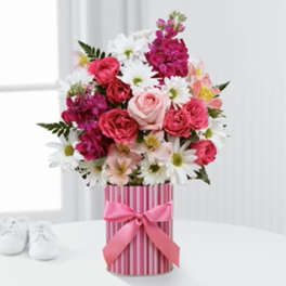 Pink and white mixed flower bouquet in a striped gift box with a ribbon