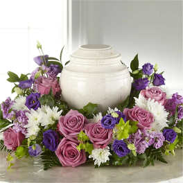 Purple and pink roses arranged around a white urn