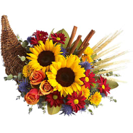 Sunflowers and mixed flowers arranged in a wicker cornucopia basket