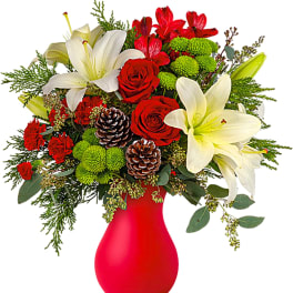 Red and white floral arrangement in a red vase with pinecones