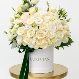 Cream rose arrangement in a white hat box with a green ribbon
