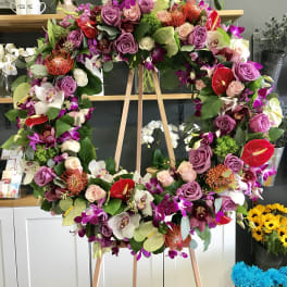 Large floral wreath on a wooden easel with purple, pink, white, and red blooms