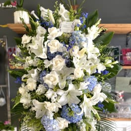 Large white and blue floral standing spray on an easel