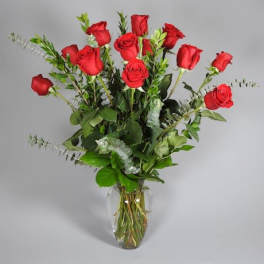 Tall arrangement of long-stemmed red roses in a clear glass vase