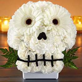 White flower arrangement shaped like a skull with dark eye and nose accents
