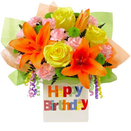 Bright bouquet of orange lilies, yellow roses, and pink carnations in a birthday vase