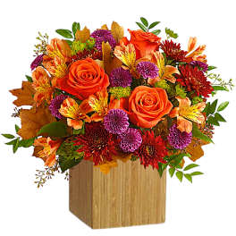 Orange roses and mixed fall flowers in a wooden cube vase