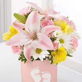 Pink and yellow flower arrangement in a pink box with baby footprints