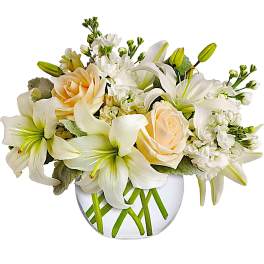 White lilies and pale peach roses in a clear glass vase