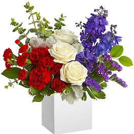 Red carnations, white roses, and purple flowers in a white box vase