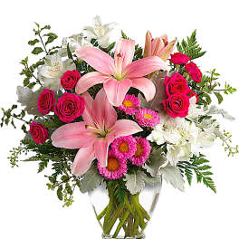 Pink lilies and roses arranged in a clear glass vase