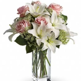 Pink roses and white lilies arranged in a clear glass vase
