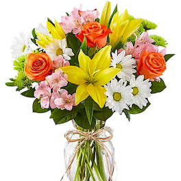 Bouquet of yellow lilies, orange roses, and white daisies in a glass vase