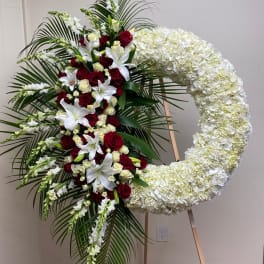 Large floral funeral wreath with red roses, white lilies, and white hydrangeas