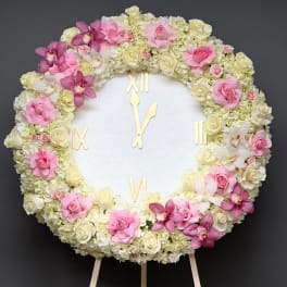 Round floral clock covered in pink and white roses and orchids