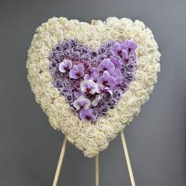 Heart-shaped floral arrangement of white and lavender roses with purple orchids