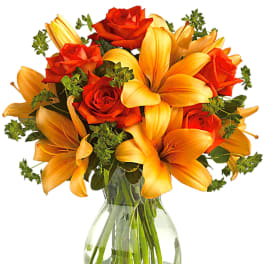 Orange lilies and red roses in a clear glass vase