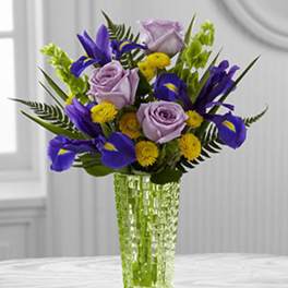 Purple roses and irises in a clear glass vase