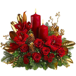 Red roses and amaryllis with two lit red candles in a holiday centerpiece