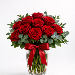 Red roses arranged in a clear glass vase with a red ribbon