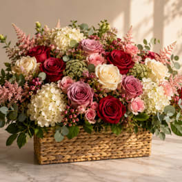 Mixed roses and hydrangeas arranged in a woven basket