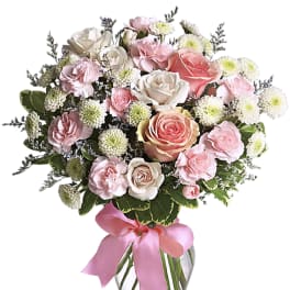 Pink and white rose bouquet in a clear glass vase with a pink ribbon