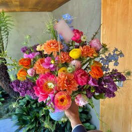 Colorful mixed bouquet in a vase with pink, orange, yellow, purple, and blue flowers