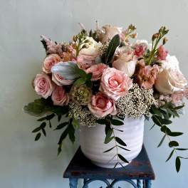Pink and white rose arrangement in a white vase