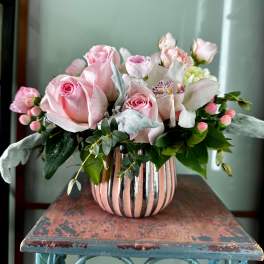 Pink roses and white blooms arranged in a striped vase
