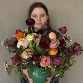 Mixed bouquet in a green ceramic vase with burgundy, pink, orange, and cream blooms