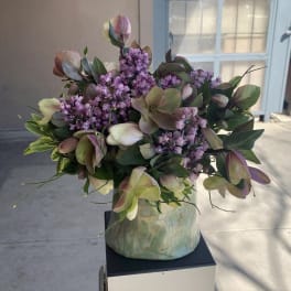 Bouquet of purple flowers and green foliage in a ceramic vase
