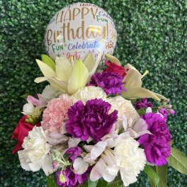 Birthday balloon above a mixed bouquet in a glass vase