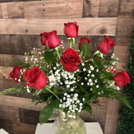 Red roses arranged in a clear glass vase with white baby's breath