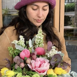 Woman holding a colorful bouquet of pink, yellow, and green flowers