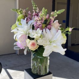 White lilies and pink flowers arranged in a clear glass vase